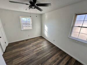 a bedroom with two windows and a fan