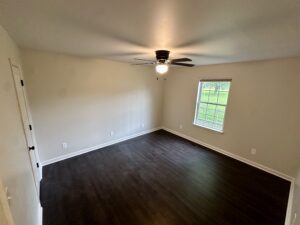 Empty bedroom with dark hardwood floors.