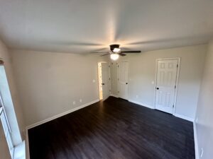 Empty bedroom with dark hardwood floors.