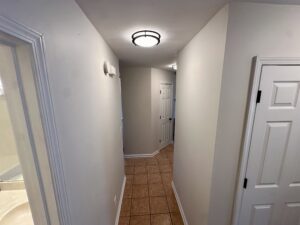 White hallway with tiled floor and doors.