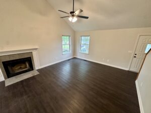 Empty living room with fireplace and windows.