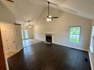 Empty living room with fireplace and hardwood floor.