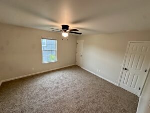 Empty bedroom with carpet and ceiling fan.