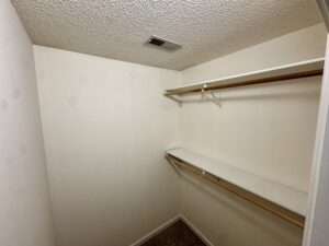 Empty closet with white shelves and rods.