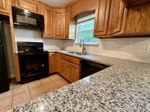 Granite countertop kitchen with stainless steel sink.