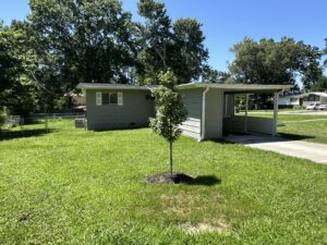 Gray house with green lawn and trees.