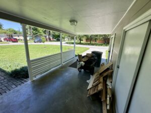 Covered porch with a wheelbarrow and wood.