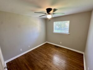 Empty bedroom with hardwood floors and window.