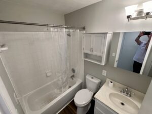 White bathroom with shower, toilet and sink.