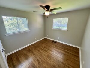 Empty bedroom with hardwood floors and windows.