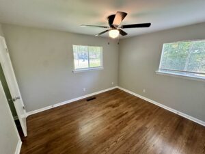 Empty bedroom with hardwood floors and windows.