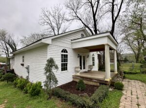 White house with porch and landscaping.