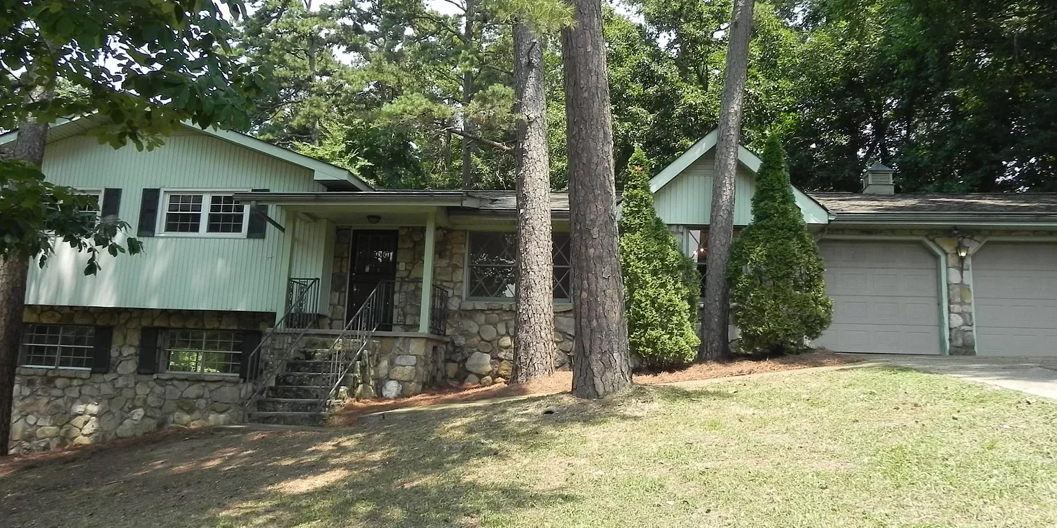 A house with trees in the background and grass on the ground.