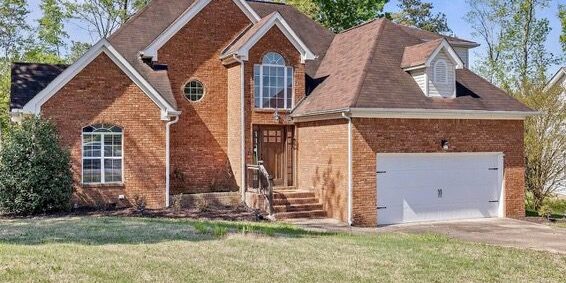 A large brick house with a sloped roof and a spacious garage.