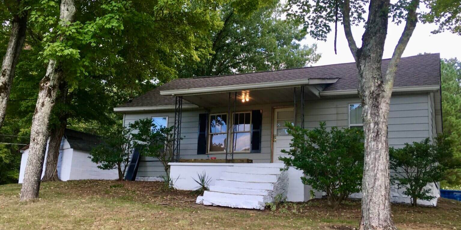 A house with a tree and bushes in front of it