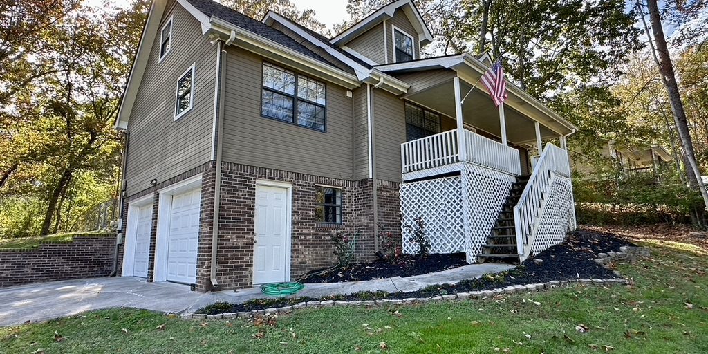 A two-story house with an exterior staircase and a partly stone foundation.