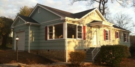 Green ranch-style house with red shutters
