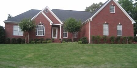 Red brick house with manicured green lawn