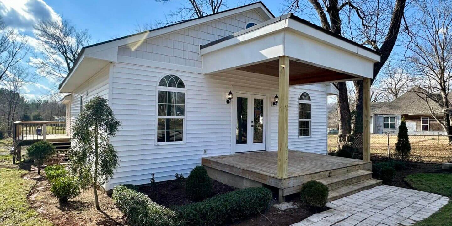 Cozy white house with a welcoming front porch and arched window.