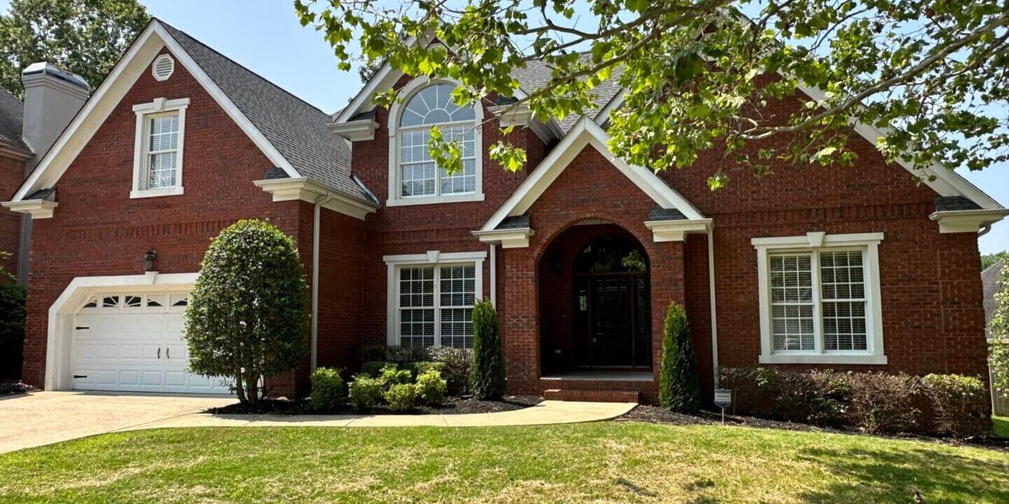 A large brick house with a tree in front of it.