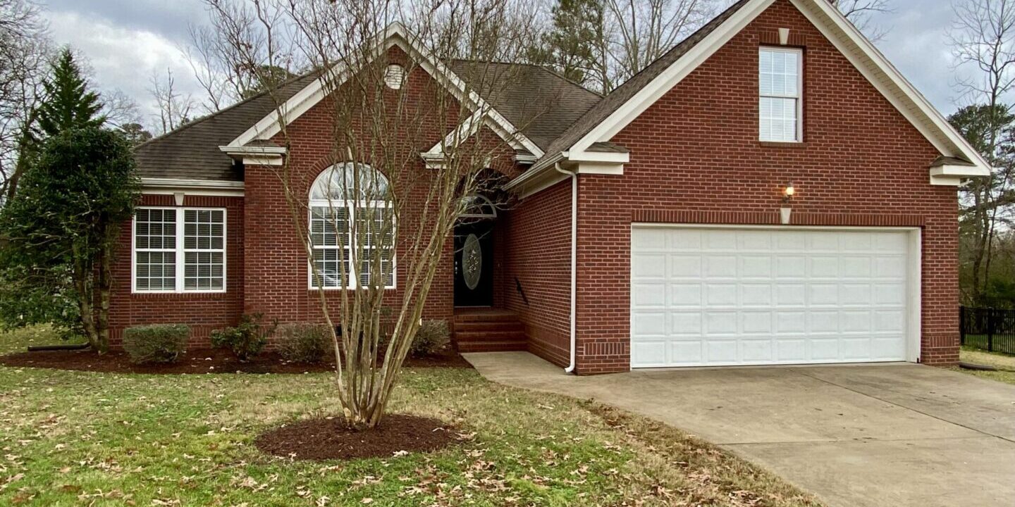 A brick house with a tree in front of it.